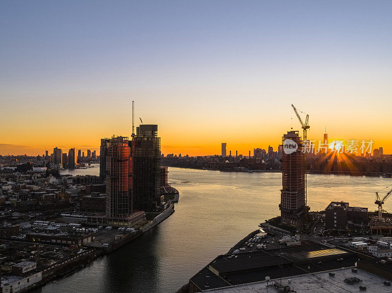 在布鲁克林绿点(Greenpoint)的东河(East River)滨水区和皇后区(Queens)的猎人点(Hunters Point)，在纽敦溪(Newtown Creek)附近，新建的豪华住宅塔楼正在建设中，日落时可以看到曼哈顿的天际线。